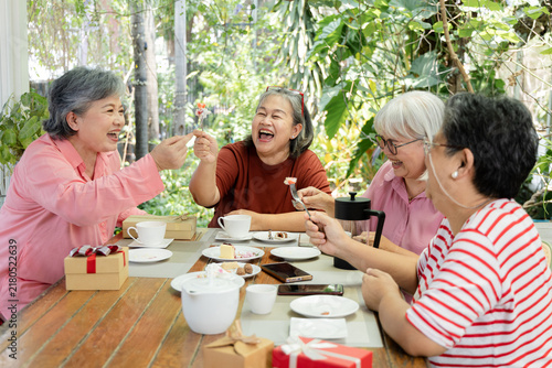 Фотография A group of friends talks over tea and cake at an outdoor cafe, sharing smiles and conversation during a relaxed reunion that celebrates companionship and warm meaningful time together, aging society