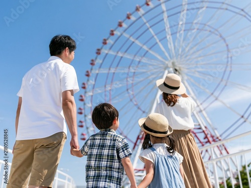 Plakat 晴天の遊園地で大きな観覧車を笑顔で見上げる仲睦まじい家族の後ろ姿