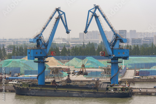 Photography Commercial cargo barge undergoing loading operations at a riverside quay near Shanghai, with bulk material being transferred aboard the vessel