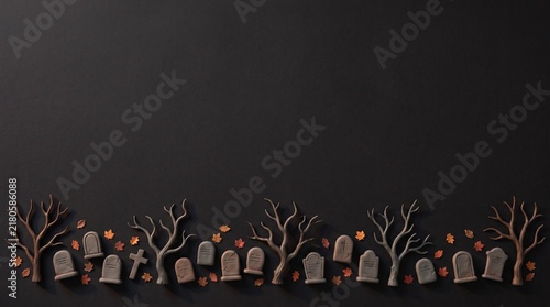 A spooky halloween graveyard scene featuring miniature tombstones and bare trees against a dark black background
