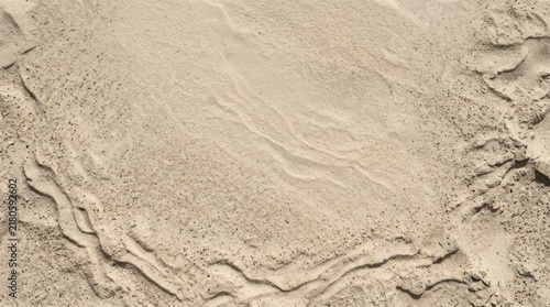 Abstract top down view of desert sand surface featuring organic wind patterns and ripple marks on sandy terrain