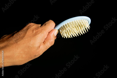 Close up of hand holding hairbrush isolated on black background