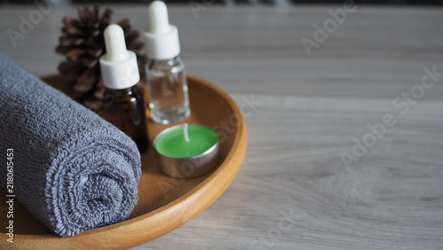 Quadro su tela Gray rolled spa towel with green tealight candle and essential oil bottles on a wooden tray, creating a calm wellness, aromatherapy, relaxation and self care concept with copy space