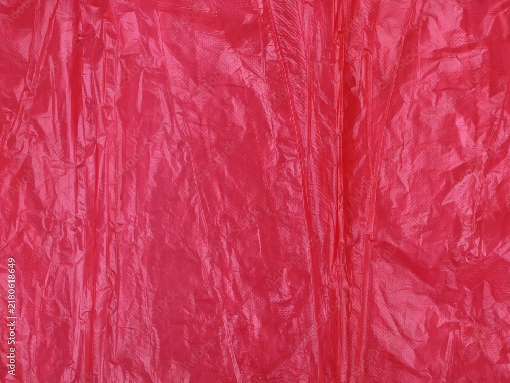 Obraz premium Close up of the texture of bright red wrinkled plastic film. Creased surface, folds, and highlights create a detailed abstract background, perfect for design, packaging concepts, or overlays