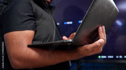 Detailed view of a software developer working on a laptop in a contemporary office environment with programming code visible on the screen