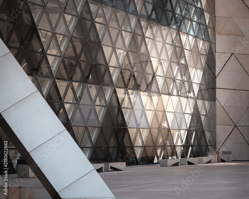 Abstract architecture, modern building wall made of many glass triangles, internal glow