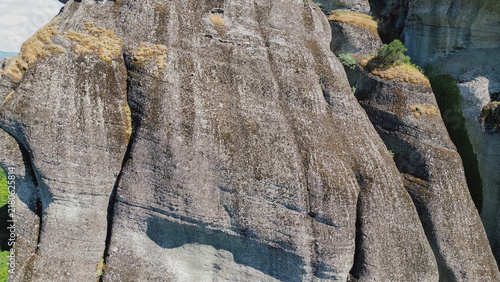 Foto Large rock formation with textured surface and patches of grass, surrounded by l