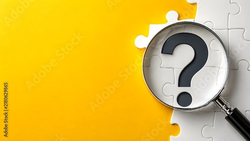 Magnifying glass over a white puzzle piece with a question mark. Concept of problem solving and finding business solutions.