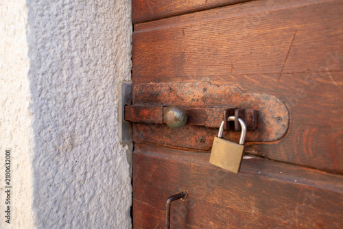 Close-up of aged wooden door secured with heavy padlock