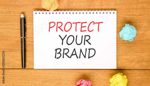 Protect your brand words symbol. Concept words Protect your brand on beautiful white note. Beautiful wooden background. Colored paper. Business and protect your brand concept. Copy space.