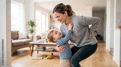 Stressed mother experiencing back pain while playing with toddler at home