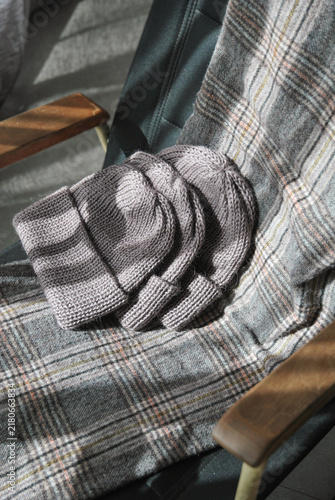 Canvastavla Stack of grey and graphite hand knitted wool beanie hats on soft plaid wool blan