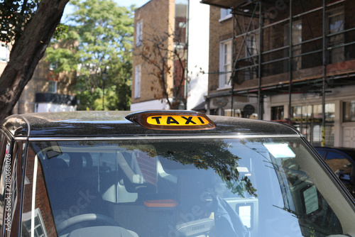 Photography Yellow taxi sign on the roof of a traditional black cab in London street