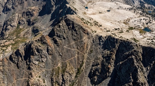 An aerial photograph showcases a rugged mountain range with steep, rocky cliffs and exposed granite.
