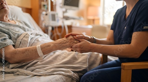 Caregiver Comforting Elderly Patient by Holding Hand Beside Hospital Bed