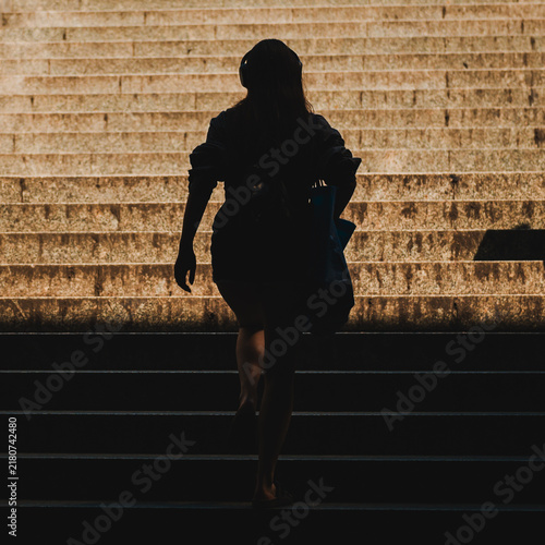 silhouette of a woman climbing stairs in the sun