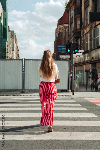 young woman in red trousers crossing at a pedestrian crossing