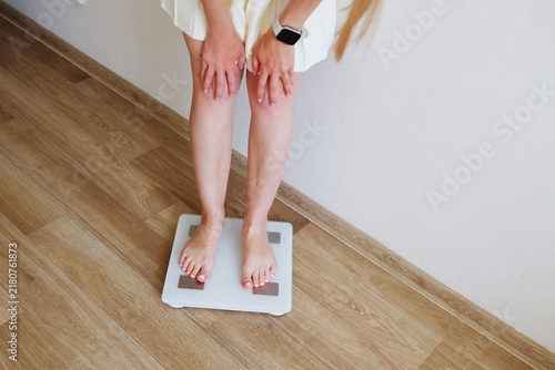 Woman using a smartphone on a smart scale, representing digital weight tracking, fitness apps and personal health goals.