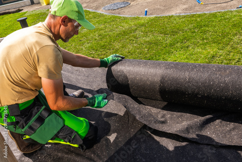 Fotografía Worker aligning black landscape fabric by hand