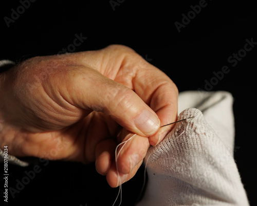 Konstfotografi Older man carefully darns a worn sock by hand, reflecting lifelong habits of thrift, self-reliance and making things last learned from growing up with little