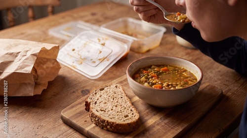 Plakat Warm hearty soup served with fresh bread on rustic wooden table