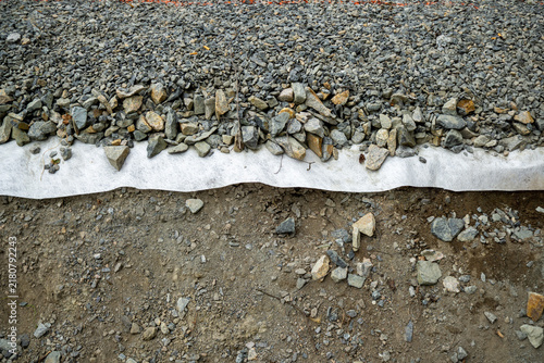 Road construction showing gravel, geotextile fabric, and soil layers