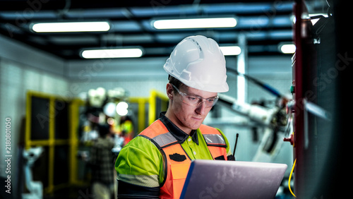 An engineer represents the future of work  using a laptop to manage AI and robotics. This high-tech automation optimizes the manufacturing supply chain.