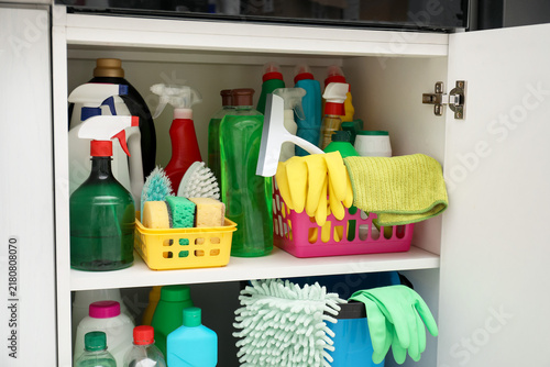 Different cleaning products and supplies in cabinet indoors  closeup
