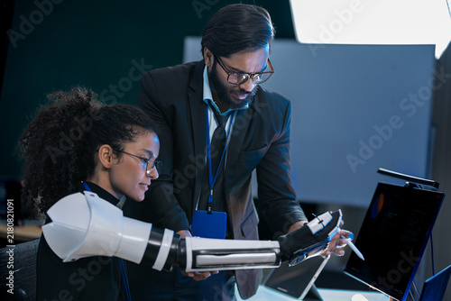 фотографія Close-up of bionic prosthetic hands in a darkroom lit by blue AI displays during a technology demonstration event at night