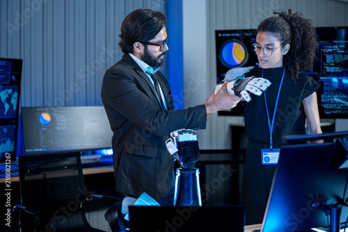 Foto Close-up of bionic prosthetic hands in a darkroom lit by blue AI displays during a technology demonstration event at night