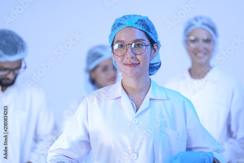 Quadro su tela A team of five researchers gives a self-assured laboratory portrait in a blue-lit laboratory while wearing white lab coats and blue protective gloves and modern scientific (No