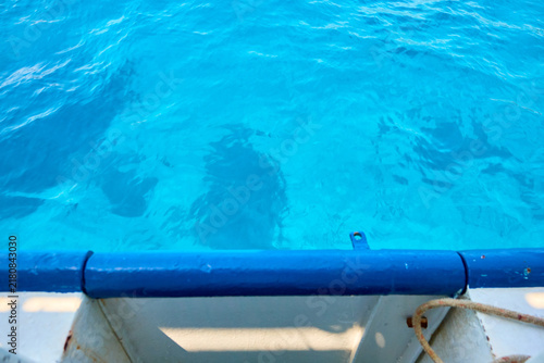 Photography Calm turquoise water ripples gently below a boat's railing
