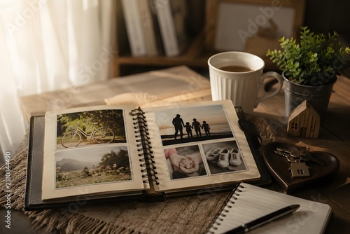 open photo album with coffee mug potted plant and keys on wooden table