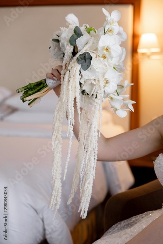 Bride holding cascading white orchid wedding bouquet side view