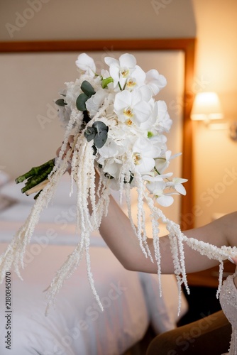 Bride holding cascading white orchid wedding bouquet side view