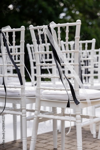 White chiavari chair decorated with black and white ribbon