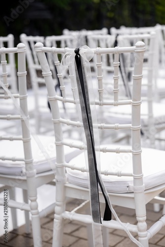 White chiavari chair decorated with black and white ribbon