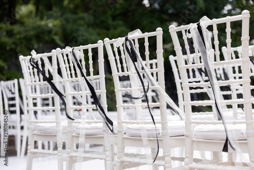 White chiavari chair decorated with black and white ribbon