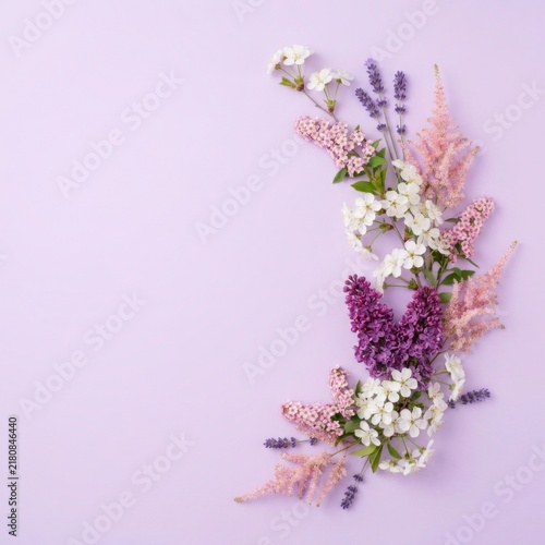 Floral composition of spring flowers arranged in a crescent shape on a soft purple background