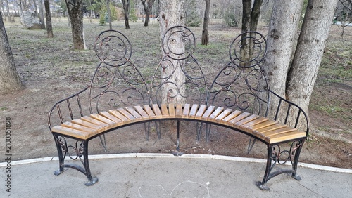 Obraz na płótnie A curved metal bench with wooden slats in a park