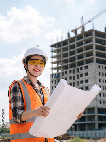 Female construction engineer reviewing blueprints at building site