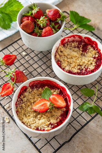 Foto Traditional English crumble cake with strawberry with backed topping  of oatmeal flour, butter and sugar in a baking dish on a stone countertop