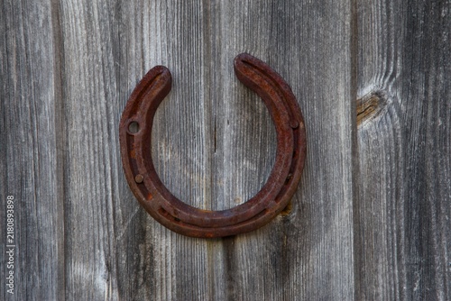 Rusted metal horseshoe symbol of good luck on weathered wooden barn wall