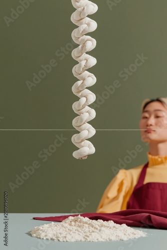 Floating coils of cinnamon dough spiraling in the air, a focused baker using a thread to cut soft floury pastry for a recipe app banner with copy space
