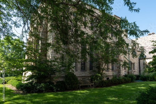 Foto Light-colored brick building partially hidden behind a lush, fluffy tree, a peac