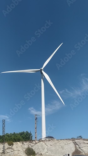 Majestic white wind turbine stands tall against a clear blue sky on a sunny day, symbolizing hope, innovation, and sustainable green energy. Great for ecological concepts. Nobody.