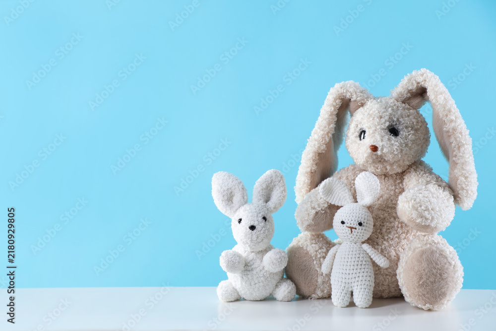 Fototapeta premium Cute stuffed toys on white table against light blue background. Space for text