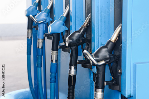 Foto Blue and black fuel pump nozzles hang in holders at a filling station
