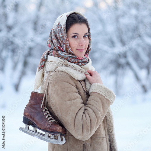 Winter portrait of a beautiful village woman in a sheepskin coat and a knitted hat