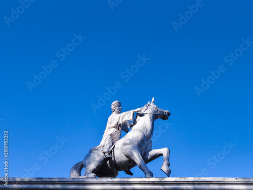 Cuadro en lienzo Horse and rider sculpture against clear blue sky, dynamic outdoor monument with